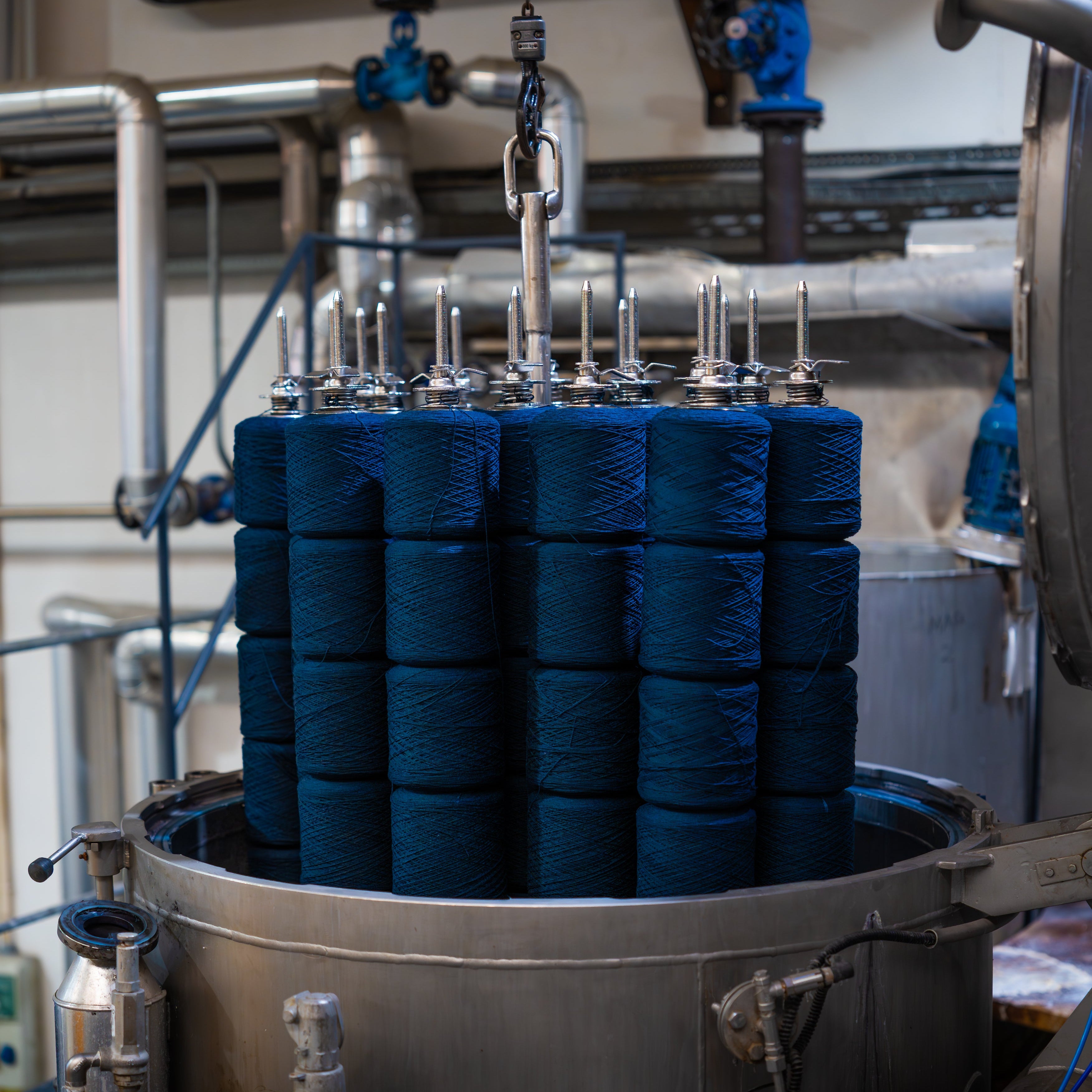 Stack of blue cylindrical objects in a industrial setting with pipes and equipment.